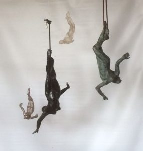 sculptures of figures hanging upside -down from the ceiling